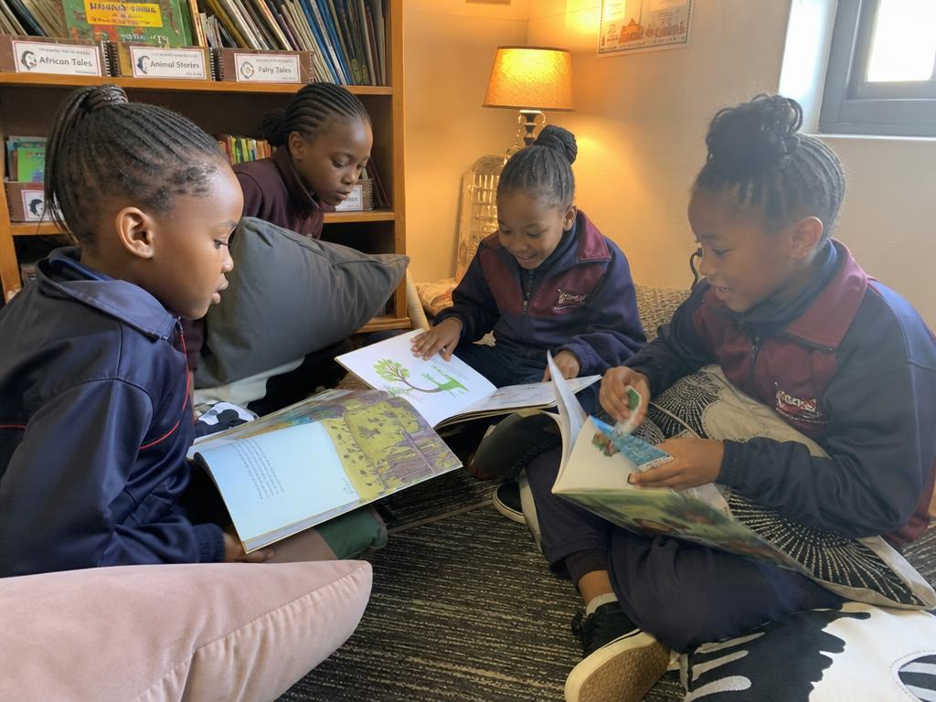 Girls enjoying story time with cushions and picture books